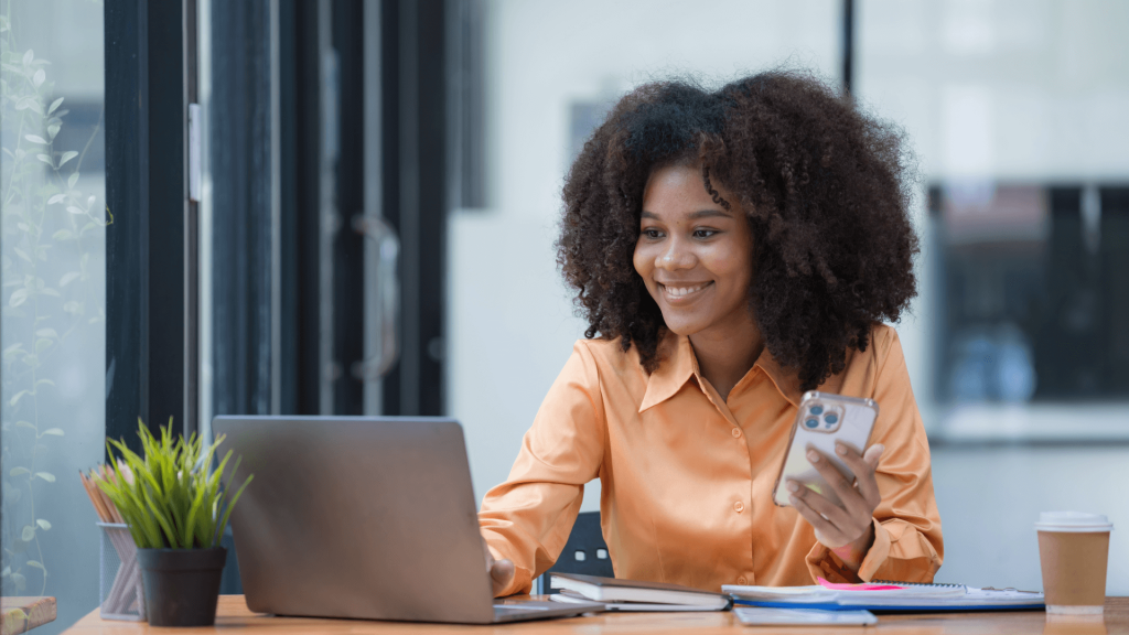 A smiling woman using a laptop to explore accident at work claims.