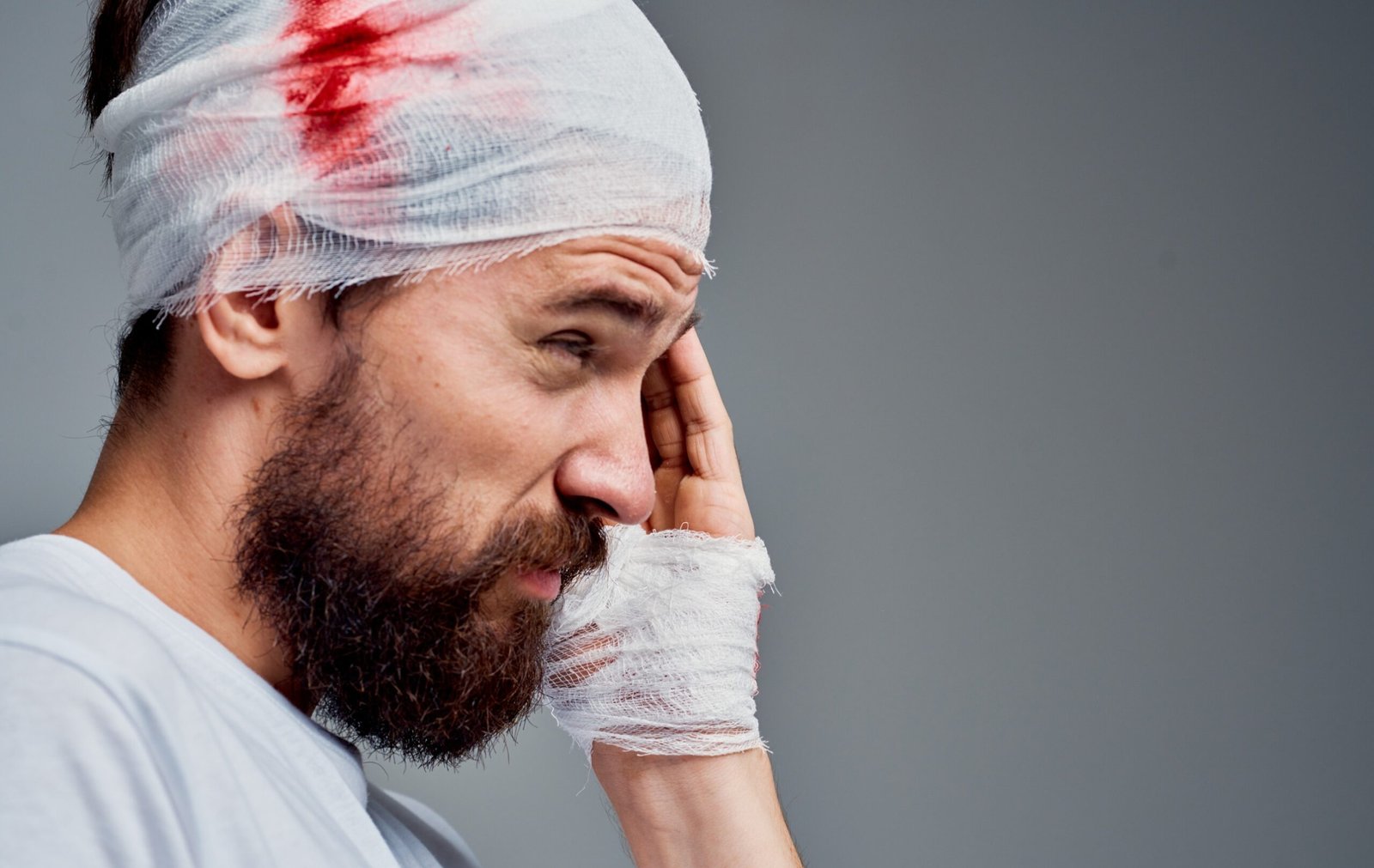 A man wearing a bandage around his head. There is some blood seeping through.